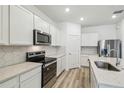 Bright kitchen featuring stainless appliances, white cabinets, hexagon backsplash, and quartz counters at 4219 Big Sky Dr, Spring Hill, FL 34604
