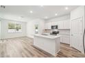 Open-concept living space with wood-look floors, a kitchen island, and plenty of natural light from windows at 4219 Big Sky Dr, Spring Hill, FL 34604