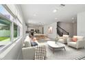 Open-concept living room with modern furnishings, sleek kitchen, and staircase leading to upper level at 4227 Big Sky Dr, Spring Hill, FL 34604