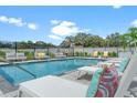 Community pool with lounge chairs, landscaping, metal fence, and blue skies at 6207 64Th N Way, Pinellas Park, FL 33781