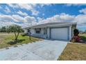 Single-story home with a one car garage, manicured lawn, and a light blue driveway at 702 W Brockton Pl # 2, Sun City Center, FL 33573