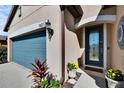 Inviting front entrance with a decorative door, blue garage door, and beautiful landscaping at 16313 Treasure Point Dr, Wimauma, FL 33598