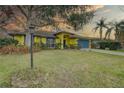 A light pole in front of the house, featuring a vibrant yellow exterior, a blue front door, and colorful landscaping at 1875 Oak Branch Dr, Sarasota, FL 34232