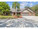 Inviting exterior of a two-story brick home, a three-car garage, and a well-manicured front yard with a palm tree at 1902 Sweet Bay Ct, Plant City, FL 33566