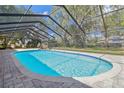 Sparkling pool in screened enclosure features brick pavers, blue trim, and lovely landscaping at 1902 Sweet Bay Ct, Plant City, FL 33566