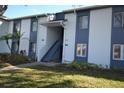 Two-story condo with blue trim, lush landscaping, and a staircase leading to the upper units at 256 Cypress Ln # 120, Oldsmar, FL 34677