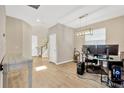 Spacious living room with wood floors, modern lighting, and a workstation setup, bathed in natural light from a window at 4071 Balcony Breeze Dr, Land O Lakes, FL 34638