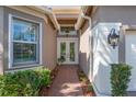 Elegant front entrance featuring double doors, transom window, and paver walkway surrounded by lush plants at 4946 Sapphire Sound Dr, Wimauma, FL 33598