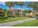 Inviting home with tropical landscaping, vibrant flowers, and a neatly maintained green lawn at 4946 Sapphire Sound Dr, Wimauma, FL 33598