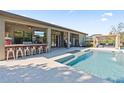 Backyard oasis featuring a covered bar and lounge area, pool with sun shelf, and lush landscaping at 15664 Starling Water Dr, Lithia, FL 33547