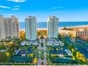 Stunning aerial view of luxurious beachfront condos, tennis courts, and lush green landscaping against a blue sky at 1170 Gulf Blvd # 2001, Clearwater, FL 33767