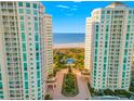 Drone shot between beachfront condos showing pristine beach, tropical landscaping, and a beautiful blue ocean backdrop at 1170 Gulf Blvd # 2001, Clearwater, FL 33767