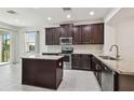 Modern kitchen with stainless steel appliances, granite countertops, an island, and dark cabinetry at 17596 Terrazzo Way, Land O Lakes, FL 34638