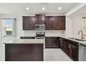 Modern kitchen featuring dark cabinets, granite countertops, stainless steel appliances, and a kitchen island at 17596 Terrazzo Way, Land O Lakes, FL 34638