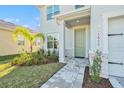 Inviting front entrance featuring a charming tiled walkway, lush landscaping, and a welcoming light-green front door at 22990 Scaglione Dr, Lutz, FL 33549