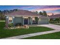 Charming single-story home with a well-manicured lawn and inviting front porch at sunset at 25950 Risen Star Dr, Wesley Chapel, FL 33544