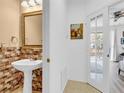 Compact half bathroom featuring a pedestal sink, tile accents, and a glass door to the bedroom at 3106 Bayshore Oaks Dr, Tampa, FL 33611