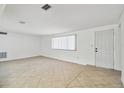 Spacious living room with neutral tile flooring, a window with blinds, and a white entry door at 3248 Rock Valley Dr, Holiday, FL 34691