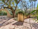 Wrought iron gates opening up to a lush courtyard with mature oak trees and brick pavers at 5020 S Shore Crest Cir, Tampa, FL 33609