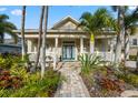 Elegant home entrance featuring a vibrant teal door, stately columns, and meticulously landscaped gardens at 5229 Brighton Shore Dr, Apollo Beach, FL 33572