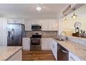 Modern kitchen featuring white cabinets, granite countertops, stainless steel appliances, and wood floors at 7902 Sailboat Key S Blvd # 206, South Pasadena, FL 33707
