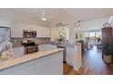 Open kitchen with white cabinets, granite countertops, stainless steel appliances, and breakfast bar overlooking the living area at 7902 Sailboat Key S Blvd # 206, South Pasadena, FL 33707