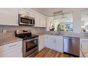 Close up of a kitchen featuring white cabinets, granite countertops, stainless steel appliances and wood flooring at 7902 Sailboat Key S Blvd # 206, South Pasadena, FL 33707