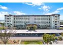 Multi-story condo building with a covered parking area, palm trees, and views of the bay at 9 Forbes Pl # 206, Dunedin, FL 34698