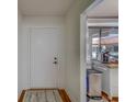 Hallway with white door, hardwood floors, gray rug, and view of the exterior through a window with sheer curtains at 2612 Pearce Dr # 310, Clearwater, FL 33764