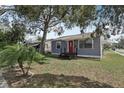 Gray single-story house with a metal roof, a bright red front door, complemented by green grass and a palm tree at 4537 22Nd N St, St Petersburg, FL 33714