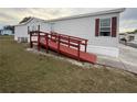 Ramped entrance of a single-story mobile home featuring red trim and neutral siding at 222 N Saint George Cir, Apollo Beach, FL 33572