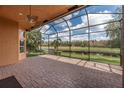 Spacious screened-in patio with brick flooring, a ceiling fan, and a serene view of the pond and trees at 5062 Stone Harbor Cir, Wimauma, FL 33598