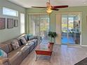 Relaxing living room features neutral green walls, sliding glass doors to a screened patio, and a comfortable gray couch at 1219 Huntington Greens Dr, Sun City Center, FL 33573