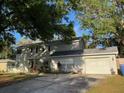 Charming two-story home with an attached garage, shaded by mature trees at 14803 Tulip Dr, Tampa, FL 33613