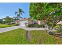 Inviting home exterior features a well-maintained lawn, palm trees, and a screened garage at 1912 Acadia Greens Dr, Sun City Center, FL 33573