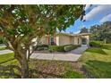 Charming home exterior with lush landscaping, mature trees, and a cozy front entrance at 1912 Acadia Greens Dr, Sun City Center, FL 33573