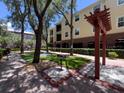 Well-maintained common area featuring a grill and outdoor seating, surrounded by mature trees at 2010 E Palm Ave # 14206, Tampa, FL 33605