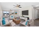 Bright living room with neutral tones, modern furnishings, ceiling fan, and large TV at 7086 Chatum Light Run, Bradenton, FL 34212