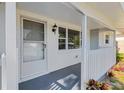 Cozy covered front porch with white pillars, brick accents and a secure screen door at 1140 7Th Ne Ave, Largo, FL 33770