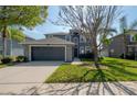 Two-story home with a two-car garage, lush lawn, and mature trees creating a welcoming atmosphere and enhancing curb appeal at 3025 Chessington Dr, Land O Lakes, FL 34638