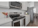 Close-up of a kitchen showcasing stainless steel appliances and white cabinets at 3025 Chessington Dr, Land O Lakes, FL 34638