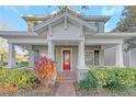 Charming home featuring a welcoming front porch, red door, and beautiful landscaping at 3622 Wiregrass Rd, New Port Richey, FL 34655