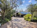 Spacious circular driveway with tropical landscaping leading to a unique home with a covered entrance at 8510 Lays Cove Pl, Odessa, FL 33556