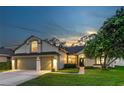 Charming single-Gathering home featuring a well-manicured lawn and a two-car garage against a picturesque evening sky at 12906 Tar Flower Dr, Tampa, FL 33626