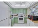 Cozy kitchen featuring retro green cabinets, white appliances, and tile flooring at 19029 Us Highway 19 N # 8-15, Clearwater, FL 33764