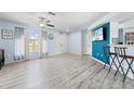Bright living room with modern floors, blue accent wall, ceiling fan, and ample natural light at 11054 Liberto Rd, Weeki Wachee, FL 34614