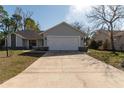 Charming single-story home with a two-car garage, set against a bright sky and surrounded by green grass at 13305 Whitby Rd, Hudson, FL 34667