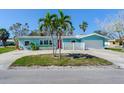 Charming coastal home with a vibrant blue exterior, red door, palm trees and a well-maintained front yard at 16312 Redington Dr, Redington Beach, FL 33708