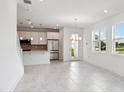 Open-concept living area with sleek flooring and a view of the modern kitchen with stainless appliances at 31857 Anchor Point Dr, Wesley Chapel, FL 33545