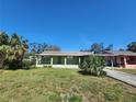 Quaint home with a well-maintained lawn and a covered carport, nestled under a clear blue sky at 6935 W Mohawk Ave, Tampa, FL 33634